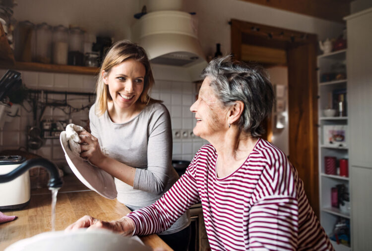 Two women smiling while washing dishes together
