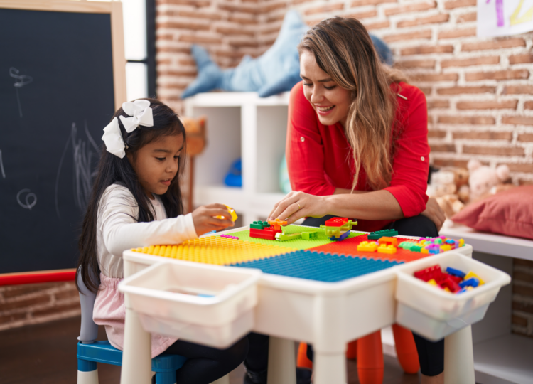 Smiling early years and childcare worker playing with young child